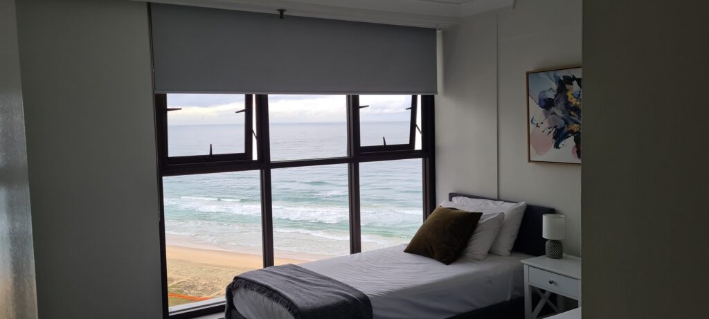 Roller Blinds On Window Overlooking The Beach