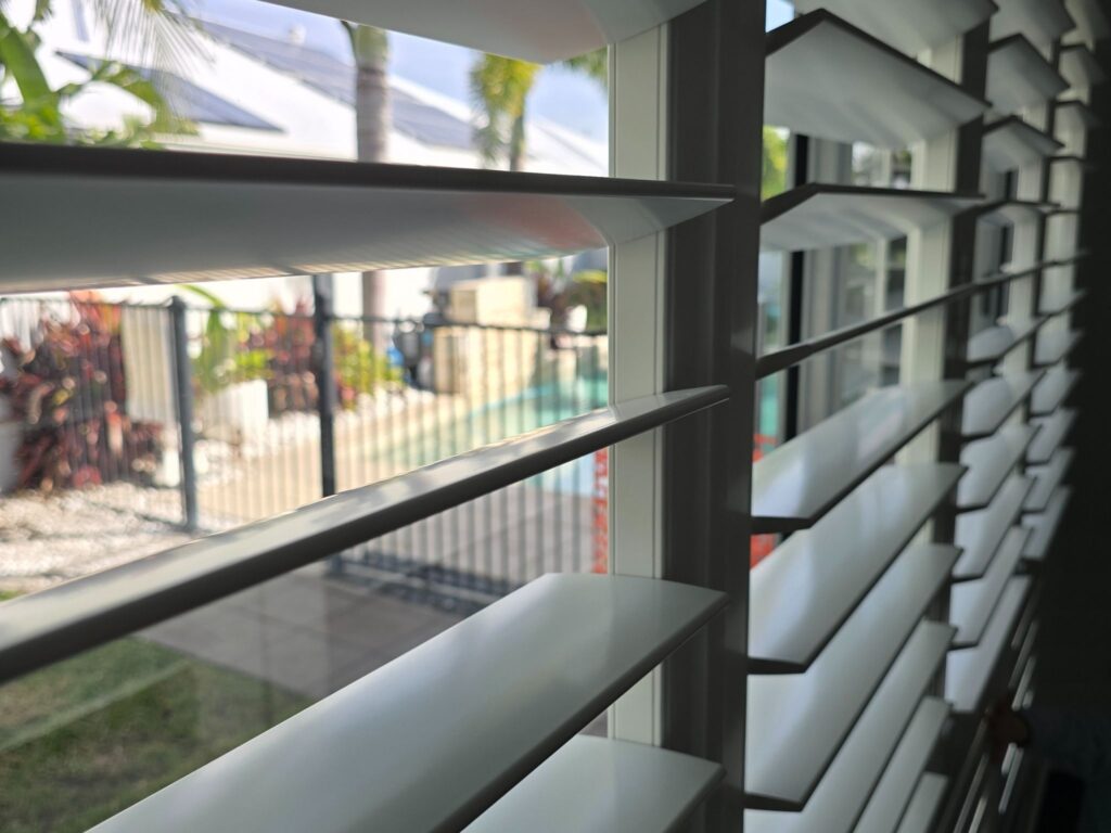 Close up view through plantation shutters to the back yard where the pool is located