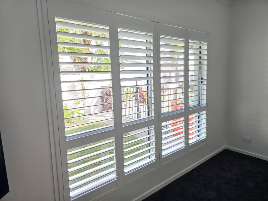 Plantation shutters on bedroom window with a view of the back yard and pool